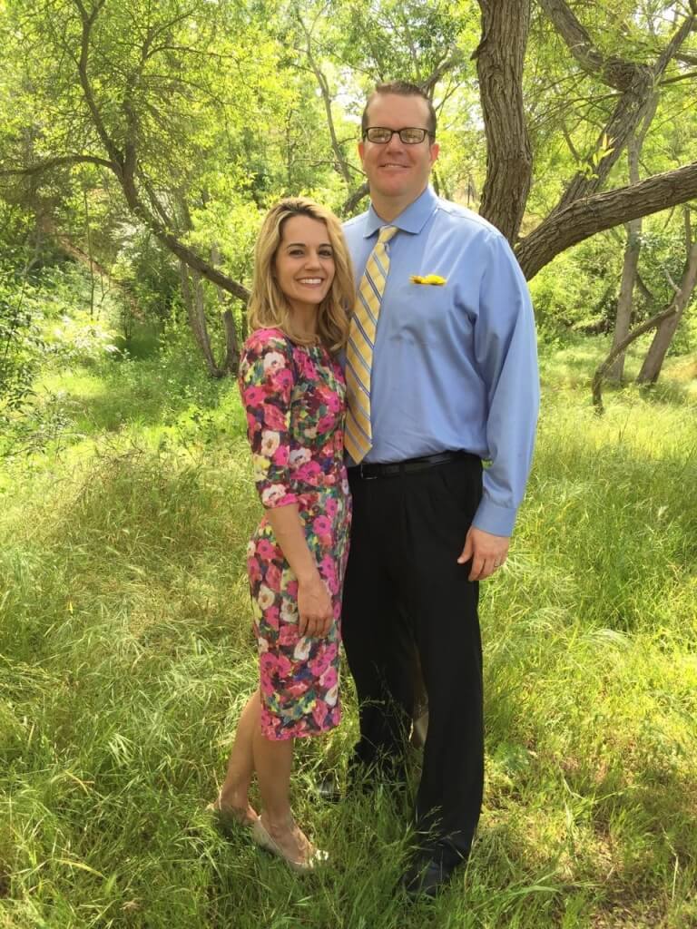 A man and woman posing in front of a tree.
