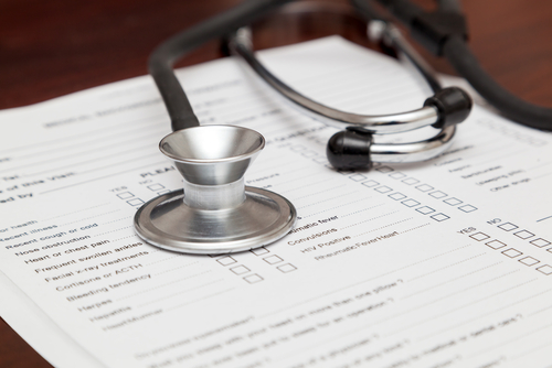 A stethoscope sits on top of a medical form.