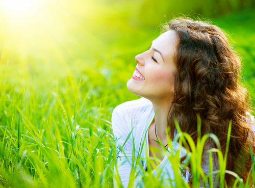 A woman lying in grass with her eyes closed.