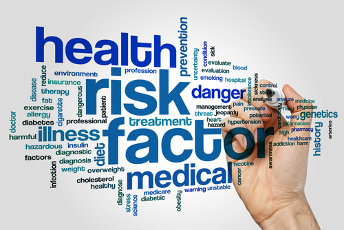 A hand writing the word health risk factor on a white background.