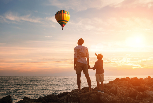 Father and son looking at a hot air balloon during the sunset